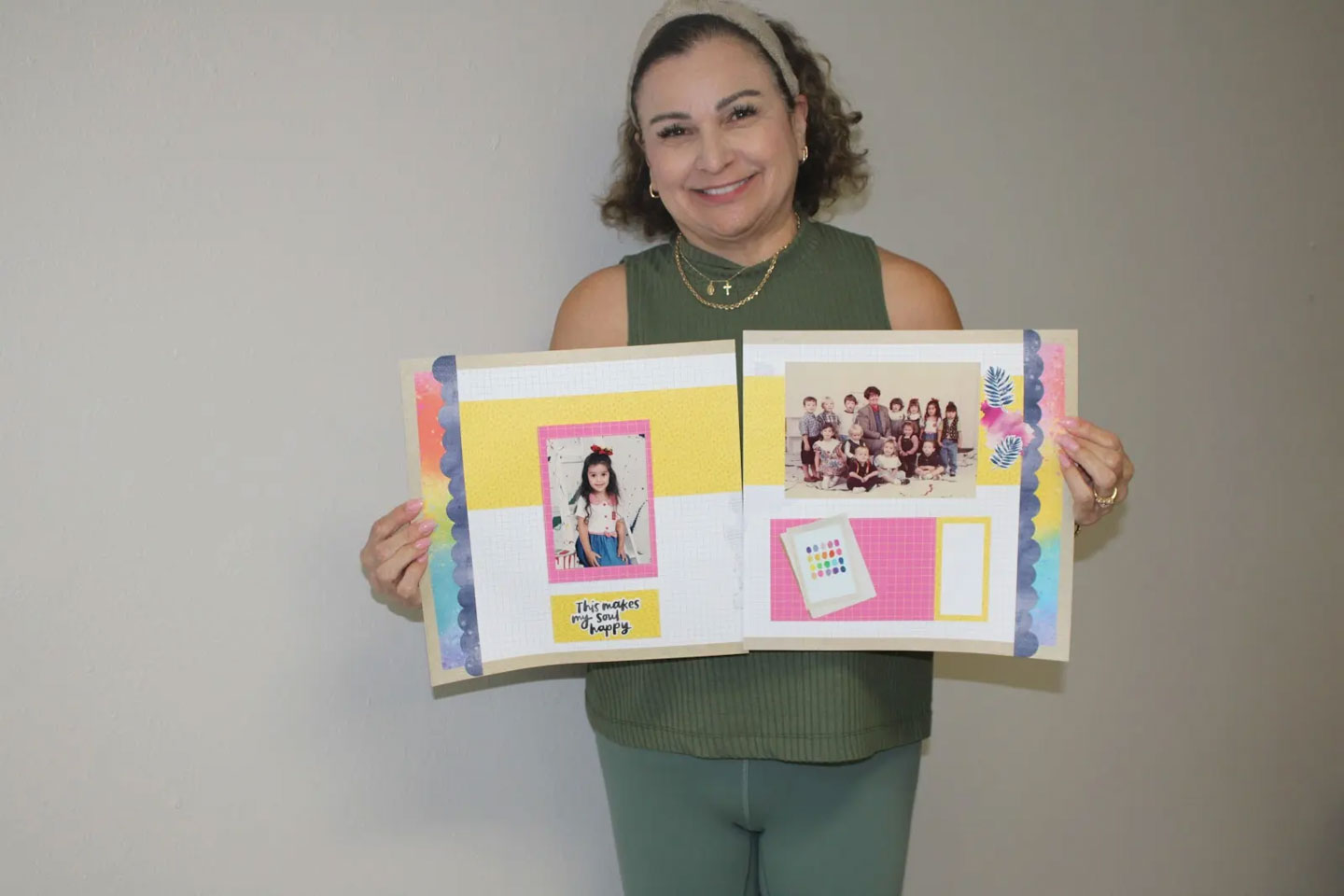 Smiling woman holding open scrapbook pages with a young girl’s photo and a group class photo.